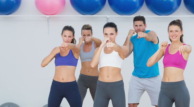 Portrait of smiling people doing power fitness exercise at yoga class in fitness studio