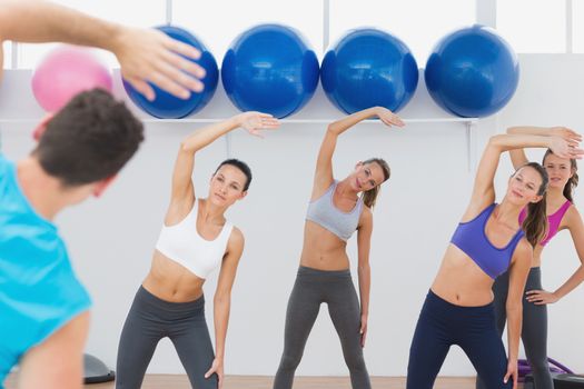 Instructor and fitness class doing stretching exercise in fitness studio