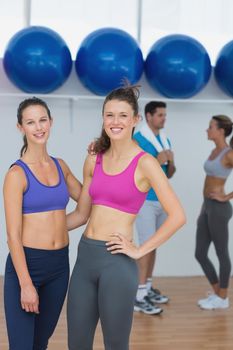 Portrait of fit young women in sports bra with a couple in background in fitness studio