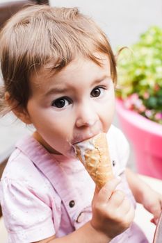 Loverly little girl eats an ice cream in cafe outdoor