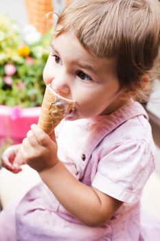 Loverly little girl eats an ice cream in cafe outdoor