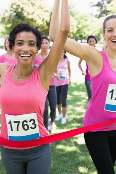 Portrait of happy female breast cancer participants winning marathon race at park