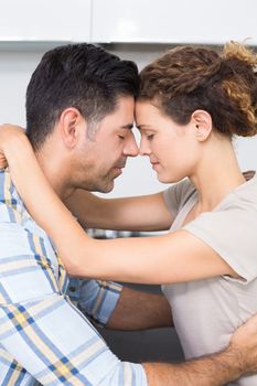Romantic couple hugging with eyes closed at home in kitchen