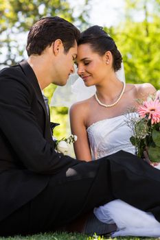 View of a romantic newlywed couple sitting in the park