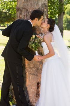 Side view of a romantic newlywed couple kissing in the park
