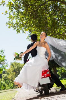 Full length of a newlywed couple sitting on scooter in the park