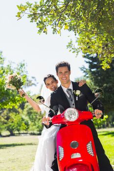 Portrait of a newlywed couple sitting on scooter in the park