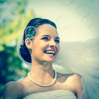 Close-up of a young beautiful bride looking at soap bubbles in the park
