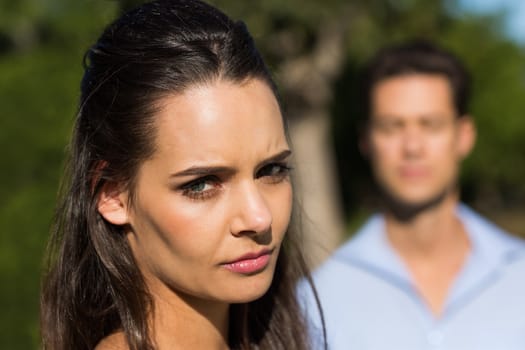 Close-up of a young woman with blurred man in the background outdoors