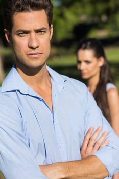 Close-up of a young man with blurred woman in the background outdoors