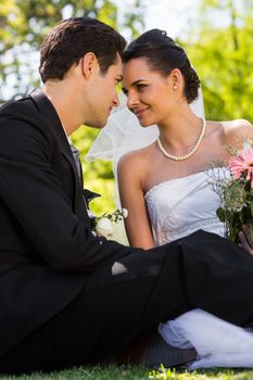 View of a romantic newlywed couple sitting in the park