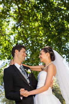 Side view of a romantic newlywed couple dancing in the park