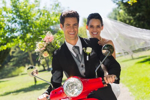 Portrait of a newlywed couple sitting on scooter in the park