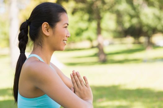 Side view of a sporty young woman in Namaste position at the park