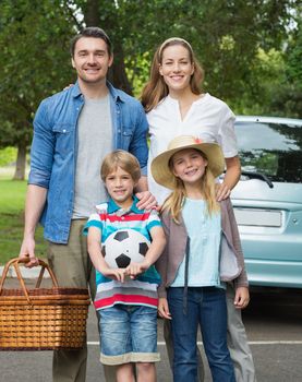 Portrait of a happy family of four with picnic basket