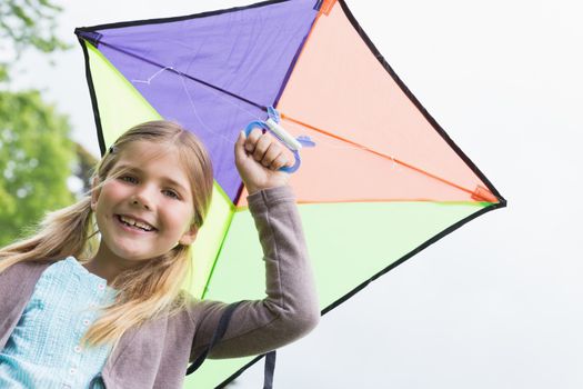 Portrait of a cute young girl with a kite standing outdoors