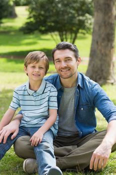 Portrait of a father and young boy sitting at the park