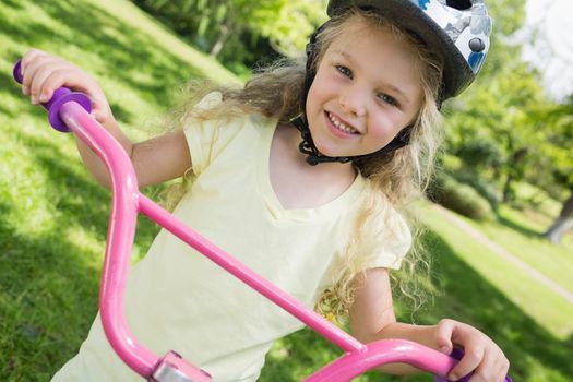 Close-up portrait of a little girl on a bicycle at summer park