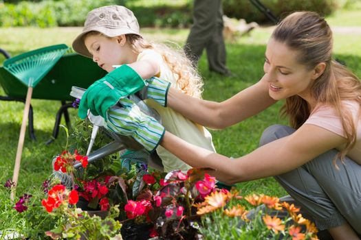 Side view of a mother and daughter watering plants at the garden