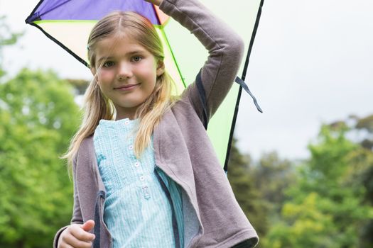 Portrait of a cute young girl with a kite standing outdoors