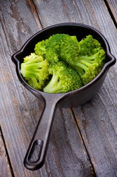 Crunchy Boiled Broccoli in Black Stew Pan isolated on Rustic Wooden background