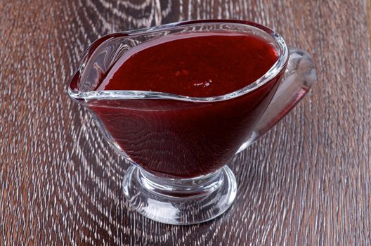 Delicious Cranberries Sauce in Glass Gravy Boat isolated on Wooden background