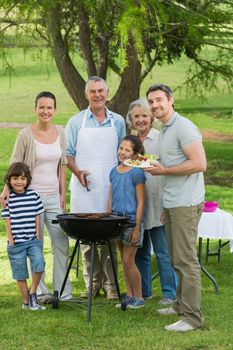 Portrait of an extended family standing at barbecue in the park