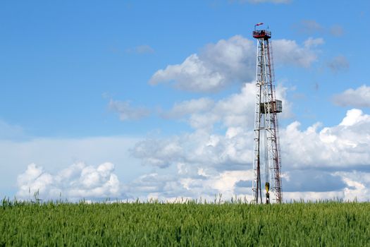 oil drilling rig on green wheat field