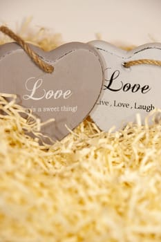 two wooden hearts in a love nest made of straw on a wooden background