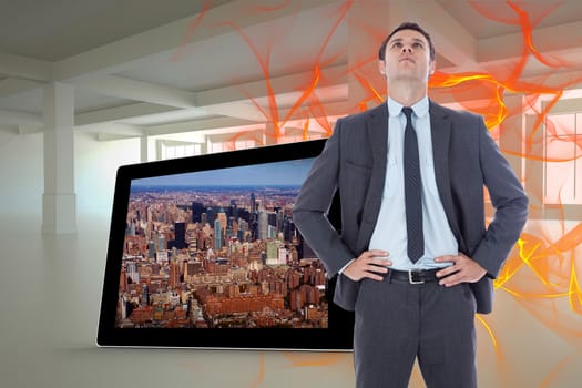 Serious businessman with hands on hips against abstract design in orange