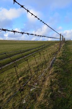 Barbed wire fence running through English fields.