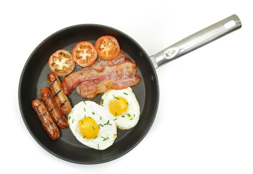 Eggs, sausages and bacon in a frying pan over a white background
