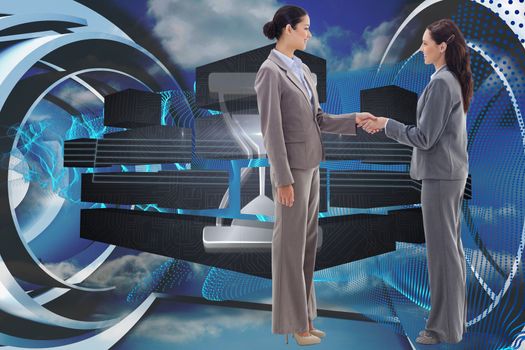 Two businesswomen shaking hands against abstract blue design in futuristic structure