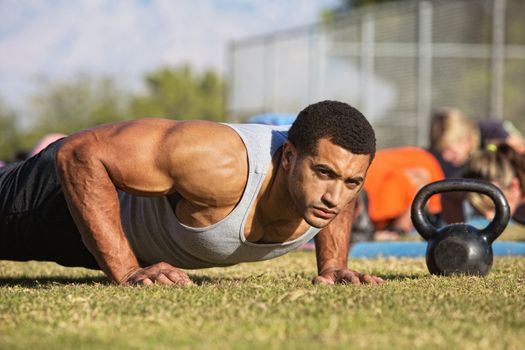 Handsome Black man with large biceps doing push-ups outdoors