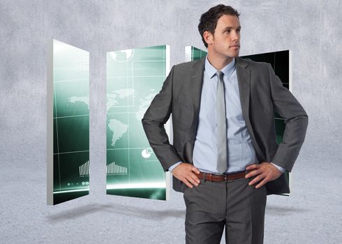 Serious businessman with hands on hips against grey wall