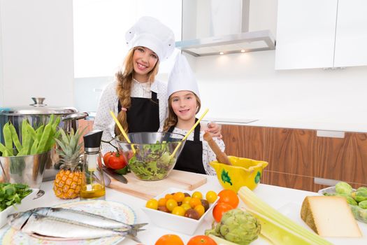 Kid girls junior chef friends hug together in countertop with food at cooking school