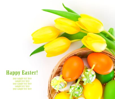 Easter eggs in a basket with yellow tulips flowers, on a white background.