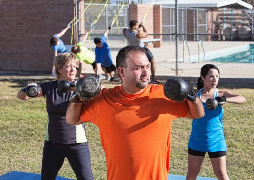 Three mature adults exercising in outdoor boot camp