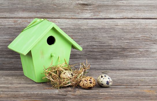 quail eggs with birdhouse, on wooden background