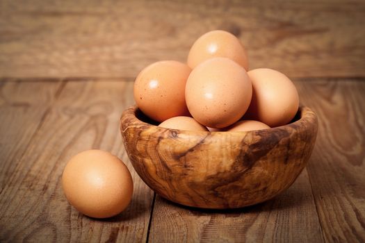 Fresh raw eggs in the wooden bowl