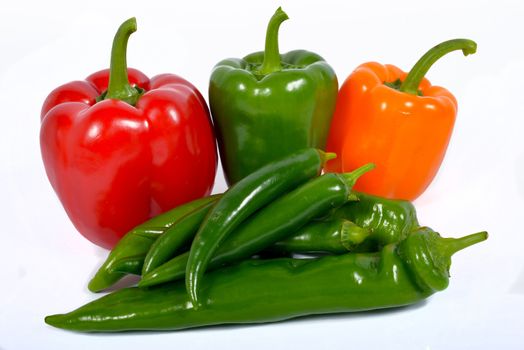 three peppers and green chillies several on the white background