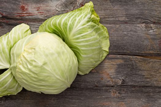 Fresh green cabbage with the outer leaves folded back to display the heart on a rustic wooden table with copyspace