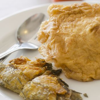 fried fish and omelet in dish with spoon and fork