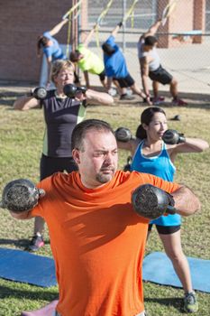 Fit mature adults exercising with weights in boot camp fitness class