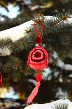 Unusual knitted Christmas decoration lying on snow-covered spruce