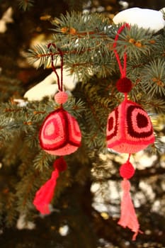 Fancy knitted Christmas decorations are on snowy spruce