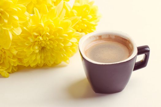 black coffee near the yellow flowers of chrysanthemums