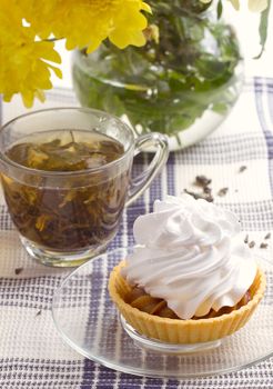 Herbal tea in glass cup and flowers on wooden table