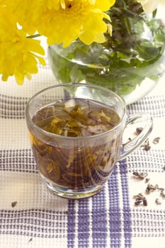 Herbal tea in glass cup and flowers on wooden table