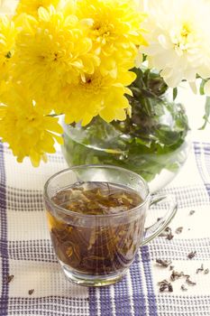 Herbal tea in glass cup and flowers on wooden table
